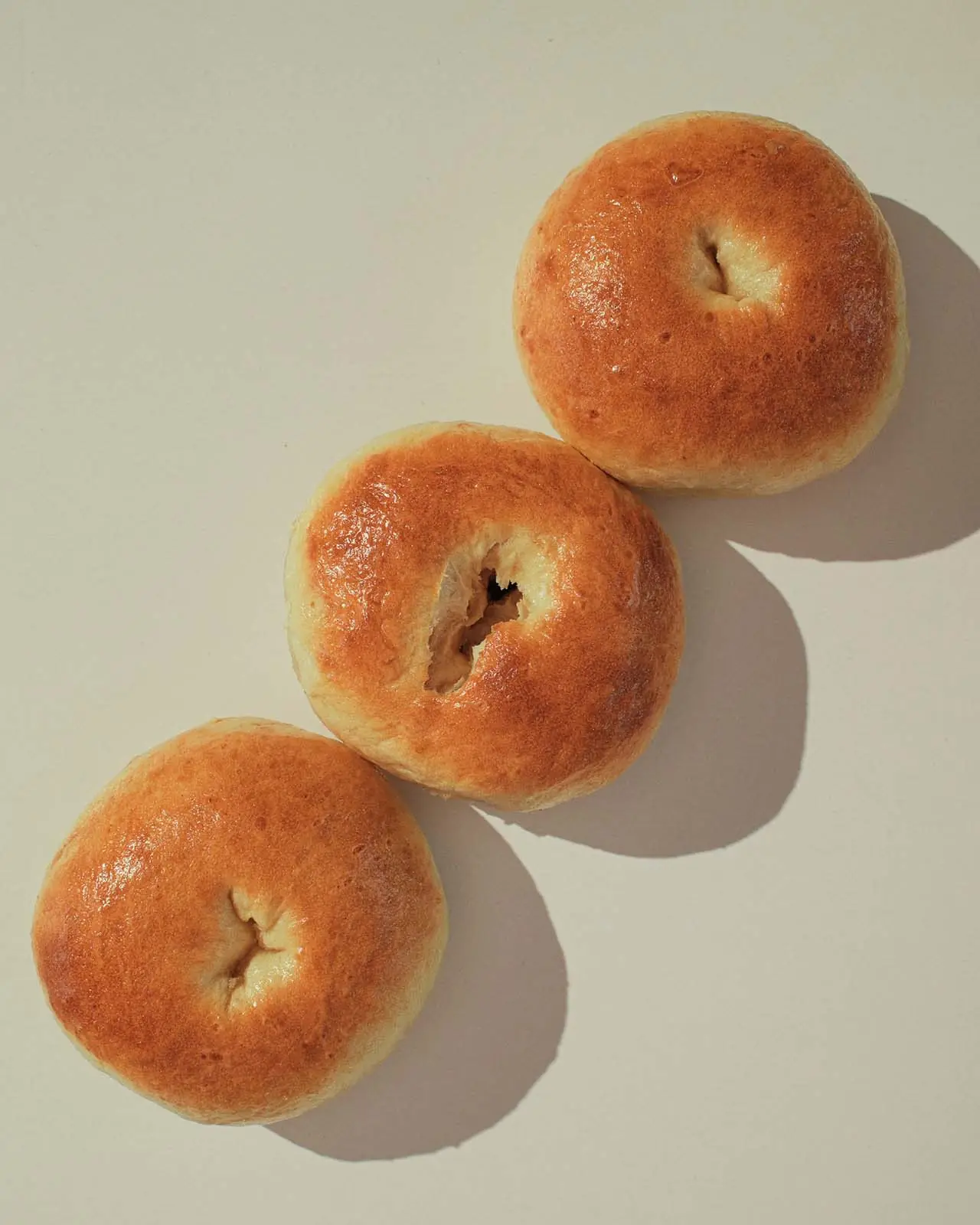 Two plain sourdough bagels, showing the shape and open crumb.