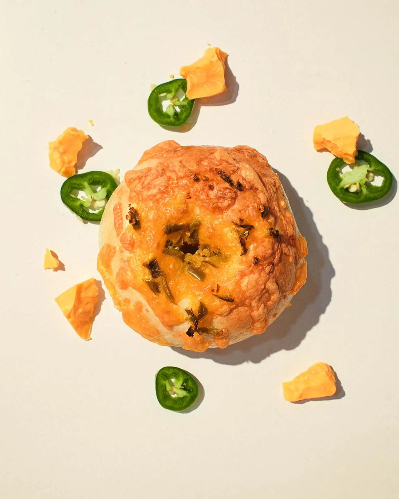 Jalapeño cheddar bagels with melted orange cheddar and charred green jalapeño across the top.