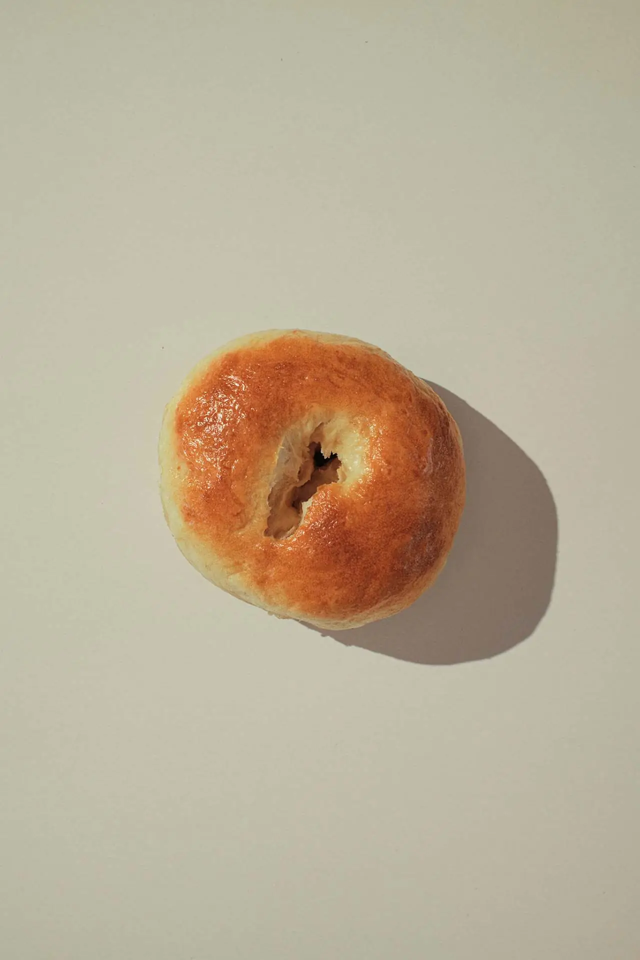 A batch of glossy golden plain bagels arranged in a circle.